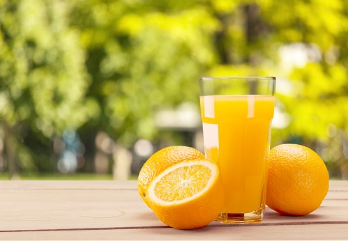 Orange juice pouring in glass on background