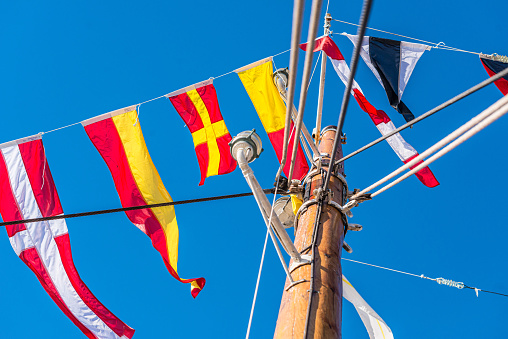 Signal flags hanging off the mast on a wooden boat.