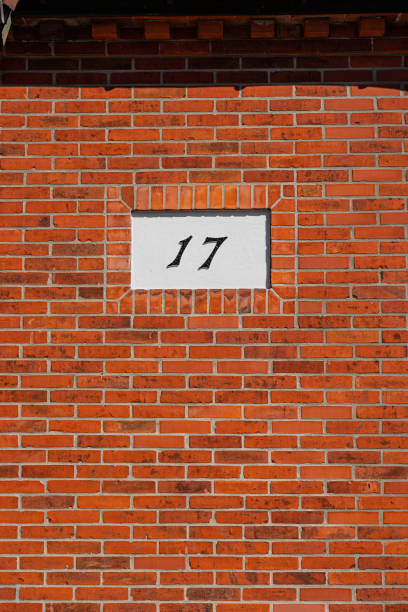 The number seventeen, 17, on a red brick wall on a house.