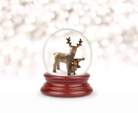 Christmas snow globe on white. Can be used as a Christmas or a New Year gift or symbol. Christmas and New Year design element. Toy glass snow globe with deer and baby. Snow ball on white.