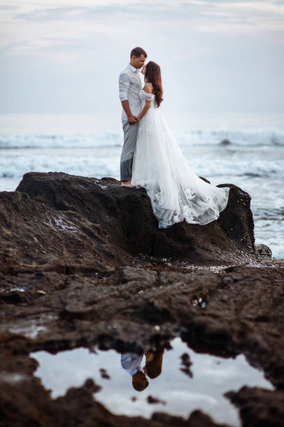 istock Elegant gorgeous bride and groom walking on ocean beach during sunset time. 1176851726
