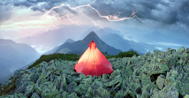 thunderstorm is dangerous for travelers A tent on top of a mountain in the Alps, a thunderstorm is dangerous for travelers, a powerful lightning bolt from storm clouds stuns with thunder and can kill ultralight photos stock pictures, royalty-free photos & images