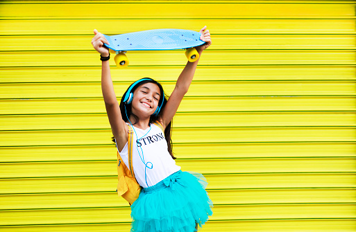 Beautiful teenage girl with skateboard dancing to the music.