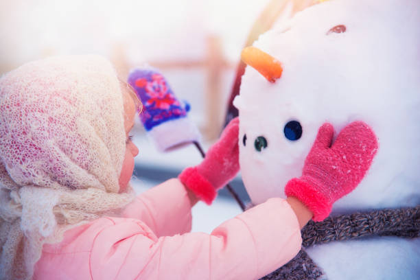istock Girl Playing with a Snowman 1176862467