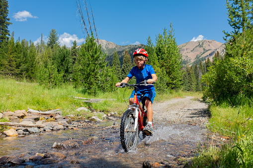7 Year Old Boy Riding Through A Creek in the Mountains