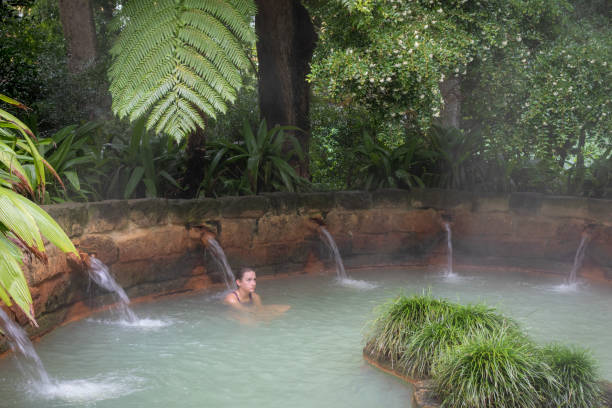 Teen girl taking massage in mineral thermal hot tub pool in the Terra Nostra botanical garden at Furnas, Sao Miguel island, Azores, Portugal. stock photo