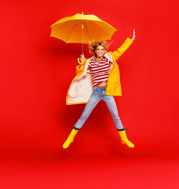 jeune fille gaie heureuse d'émotion riant et sautant avec le parapluie jaune sur le fond rouge coloré - 11877 photos et images de collection