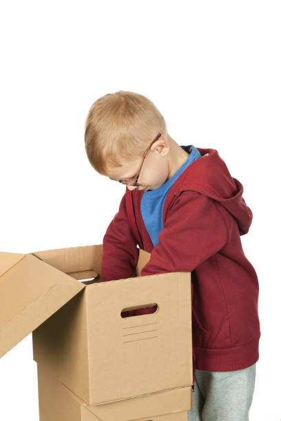istock 7 year old red-haired boy with glasses packs things in a box 1176867543