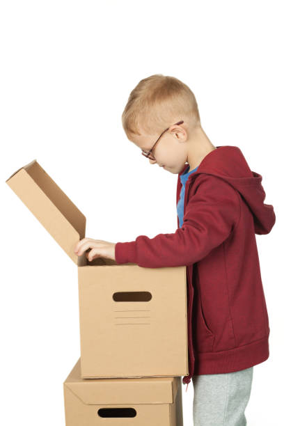 istock 7 year old red-haired boy with glasses packs things in a box 1176867553
