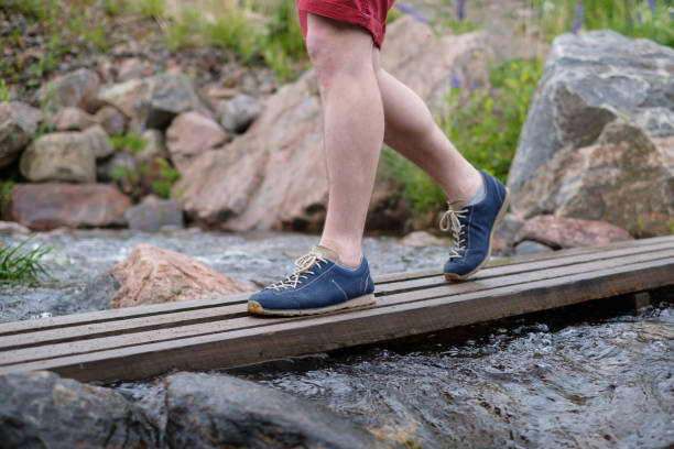 istock Man walking on a wooden bridge crossing water stream 1176867646