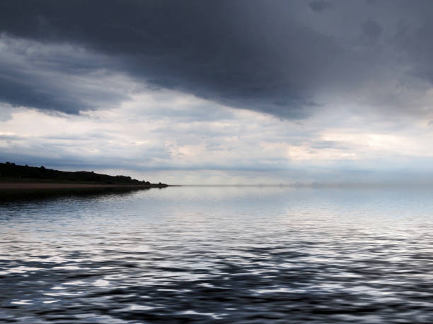 istock a distant coast reflected in the sea with dramatic dark storm clouds 1176867691