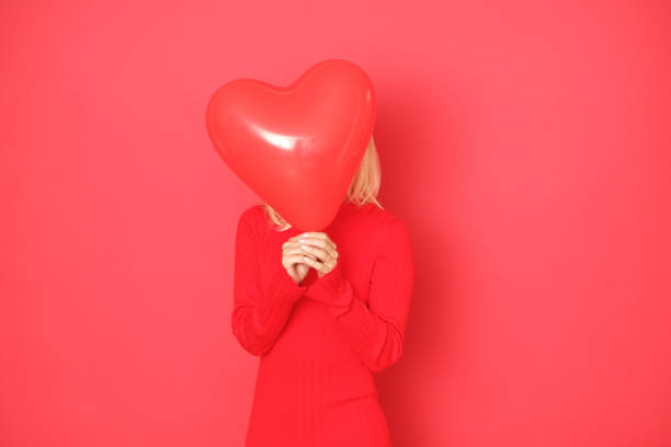istock Beautiful blonde is hiding behind the red heart shaped balloon. 1176867721