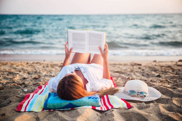 istock Beautiful woman reading on beach 1176872817