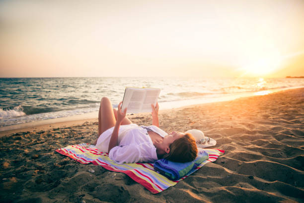 istock Woman reading a book on the beach 1176872827