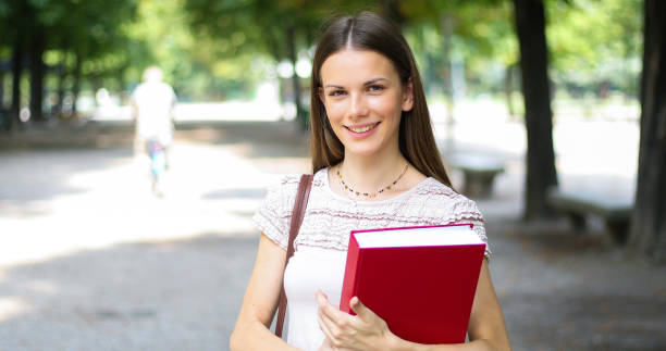 istock Smiling student outdoor holding a book 1176877112