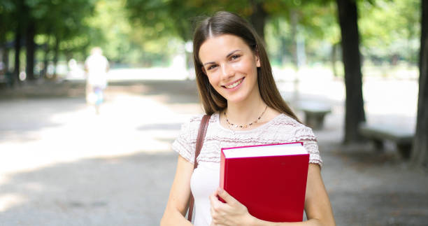 istock Smiling student outdoor holding a book 1176877116