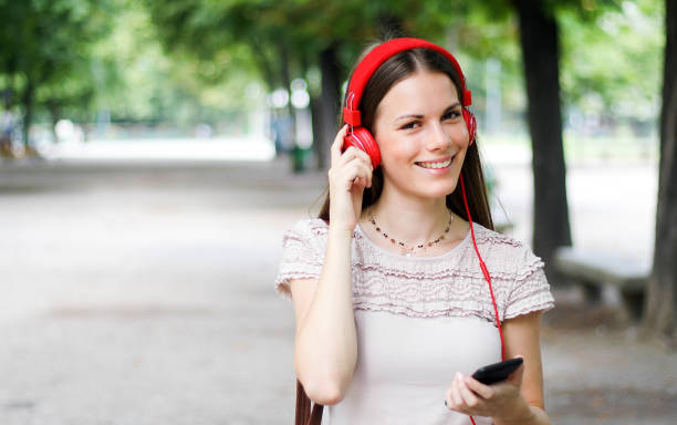 istock Woman walking in a park while using her smartphone to listen music 1176877128