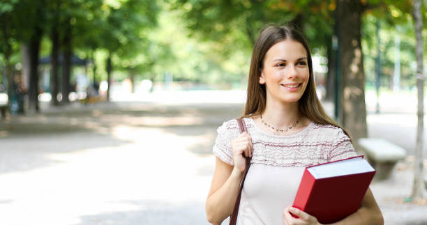 istock Smiling student outdoor holding a book 1176877138