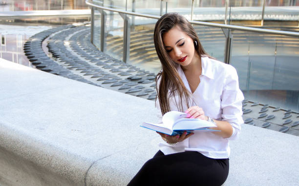 istock Young woman reading a book outdoor 1176887107