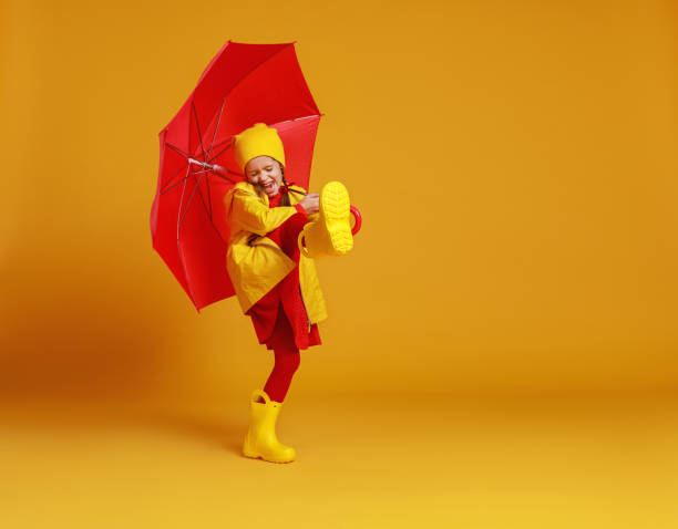 色付きの黄色の背景に赤い傘で笑う幸せな感情的な陽気な子供の女の子 - 11909 ストックフォトと画像