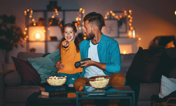 padre de familia y su hija viendo proyector, televisión, películas con palomitas de maíz por la noche en casa - 11906 fotografías e imágenes de stock