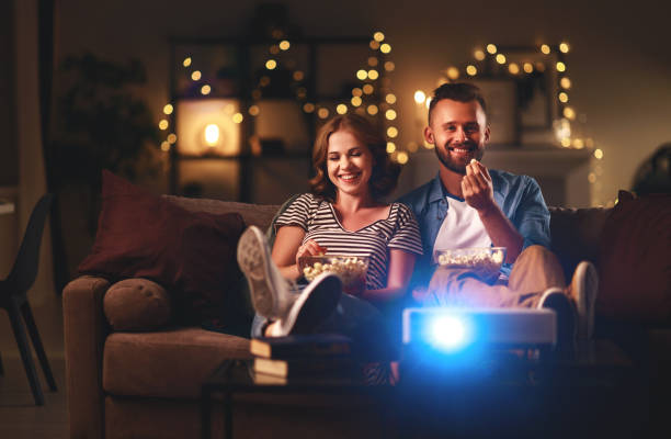 pareja familiar viendo la televisión en casa en el sofá - equipo de proyección fotografías e imágenes de stock