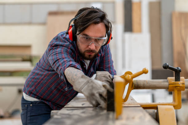 istock Carpenter cutting wood with a machine at a workshop 1176899968