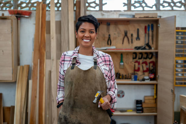 Happy Latin American carpenter smiling Portrait of a happy female Latin American carpenter looking at the camera smiling woman wearing tool belt stock pictures, royalty-free photos & images