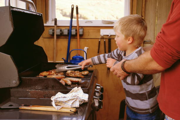 Child and Father Cooking Sausages on Barbecue