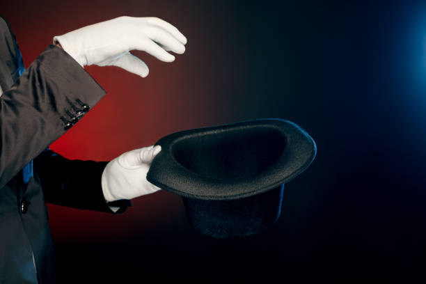 istock Professional Occupation. Showman in suit and gloves standing isolated on wall making tricks with hat close-up 1176906917