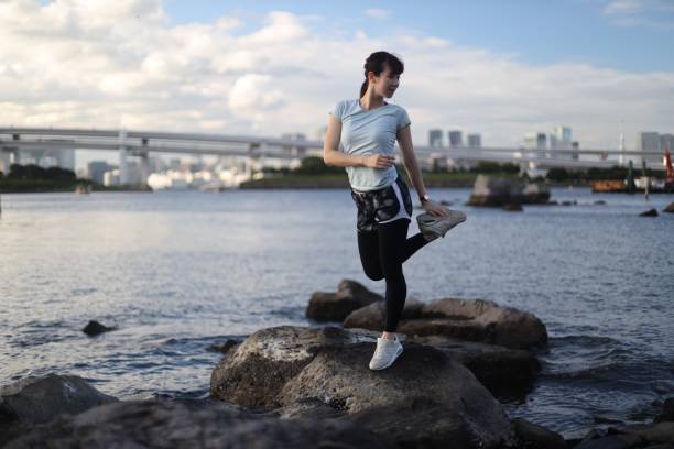 istock Young beautiful female stretching on the beach rock 1176910140