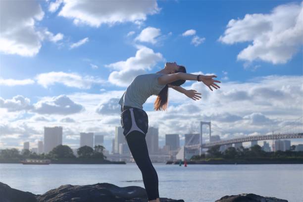 istock Young beautiful female stretching on the beach rock 1176910189