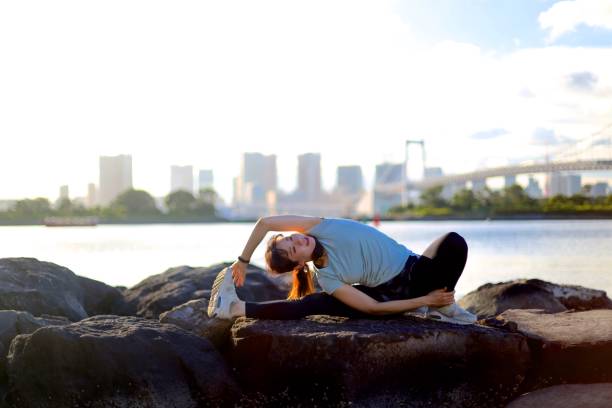 istock Young beautiful female stretching on the beach rock 1176910293
