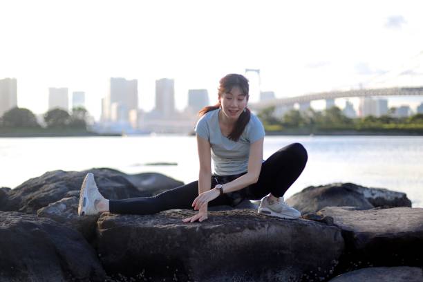 istock Young beautiful female stretching on the beach rock 1176910385