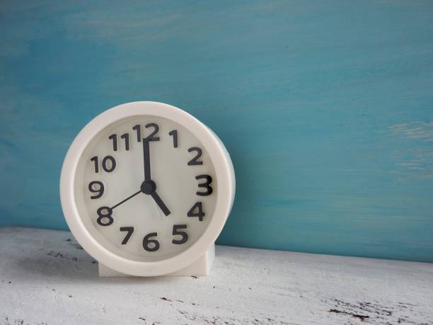 istock White clock pointing to 5 o'clock with white and light blue painted wooden background 1176912666