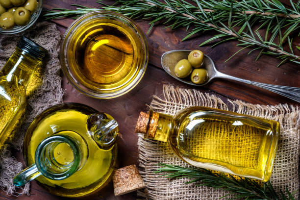 vista superior de aceitunas y botellas de aceite de oliva sobre la mesa en una cocina rústica - aceite de oliva fotografías e imágenes de stock
