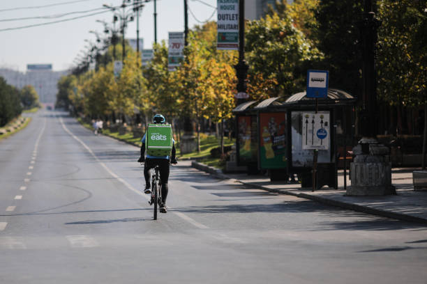 UBER Eats delivery biker on an empty boulevard during a sunny day. Bucharest, Romania - September 22, 2019: UBER Eats delivery biker on an empty boulevard during a sunny day. bucharest people stock pictures, royalty-free photos & images