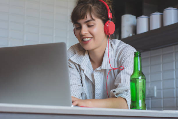 istock Young woman with beer and using her laptop 1176921977