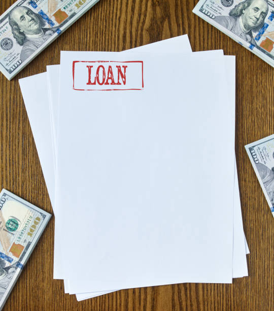 Loan Looking down on wooden desk with blank paper with “loan” stamp 100 dollar bills one hundred dollar stamp stock pictures, royalty-free photos & images