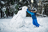 Little boy building a snowman on a winter day