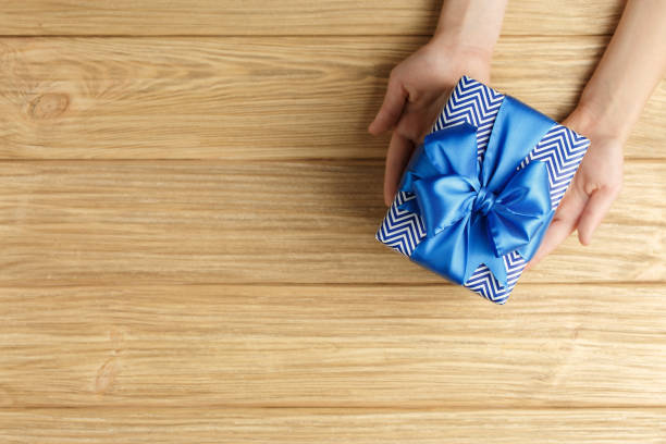 istock gift box in the hands on a wooden background top view 1176938460