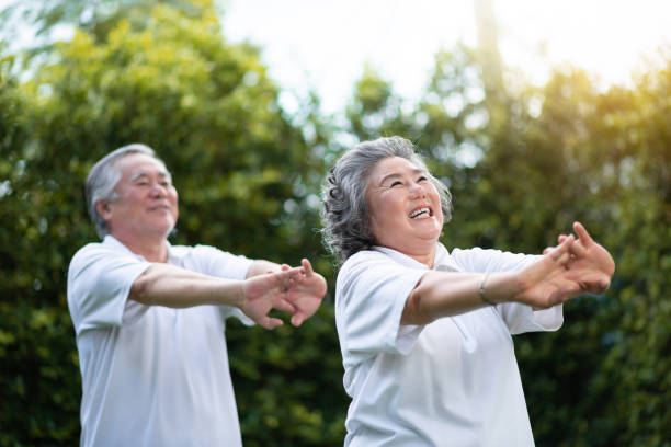 Happy Asian senior couple exercise. Happy Asian senior couple stretching hands before exercise at park outdoor. Smiling People in white shirts. chinese couple stock pictures, royalty-free photos & images