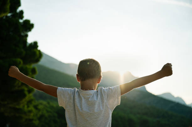 Young boy standing outside at sunrise stock photo