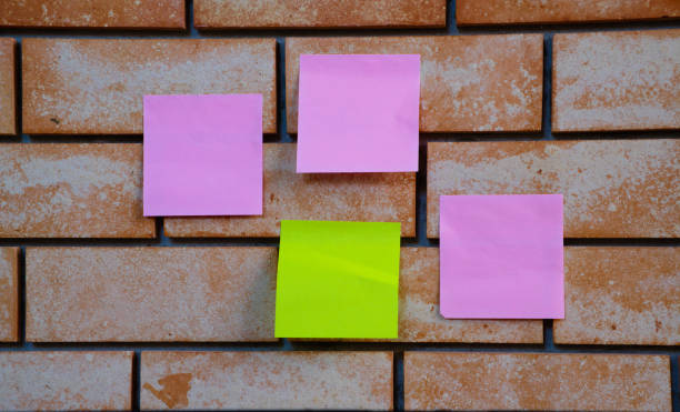 almohadilla de notas rosa y verde en la pared de ladrillo - sheet adhesive note paper note pad fotografías e imágenes de stock