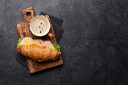 Coffee and croissant sandwich on stone table. French breakfast. Top view flat lay with copy space for your text