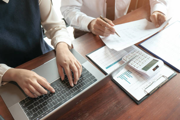 istock Businessman analyzing investment charts and pressing calculator buttons over documents. Accounting Concept. 1176954565