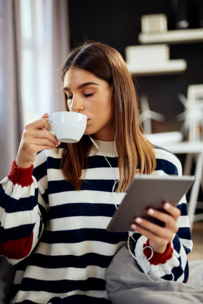 istock Woman using tablet and drinking coffee in bedroom. 1176955455