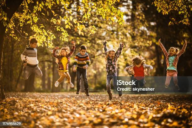 Verspielte Kleine Freunde Die Spaß Beim Springen Im Herbsttag Im Park Haben Stockfoto und mehr Bilder von Kind
