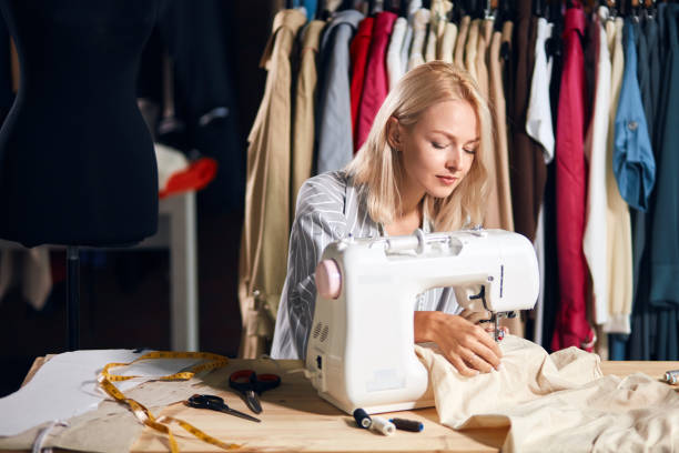 istock Young blonde serious needlewoman at studio working with sewing machine 1176957856
