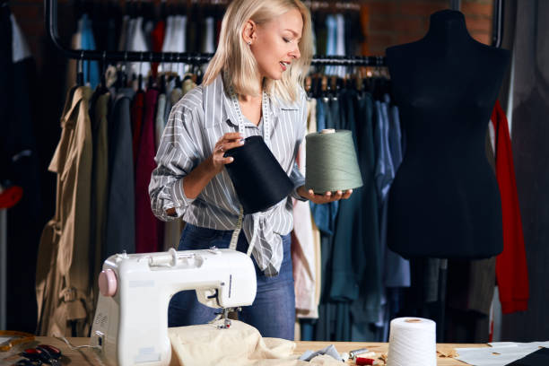 istock cute tailor holding tow big thread in hands choosing them to sew 1176957869